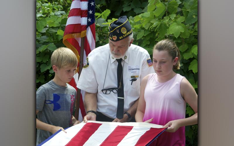 North Georgia Honor Guard member Steve Strickland helps Blue Ridge Elementary School fifth grade students Jayden Richardson, left, and Addyson Bradburn fold the American flag during a Flag Etiquette class at the school Friday, August 27.