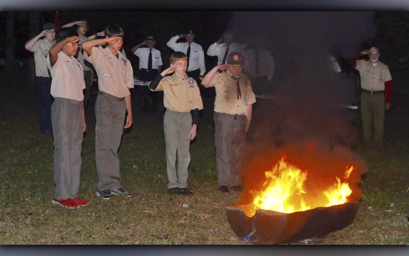 Boy Scout Troop 32 from Epworth held a Flag Retirement ceremony at Ron Henry Horseshoe Bend Park Tuesday, October 19. After placing the blue field in the fire, Boy Scout Troops, from left, Gandy Vincente, Austin Prieto, Clay Dillard and Patrick Thomas of Pack 432 salute as TAPS is played laying the retired flag to rest.