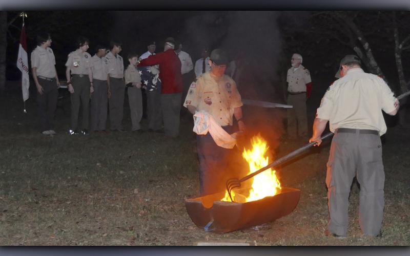 Boy Scout Roy Green of Troop 32 from Epworth places the final stripe into the fire before the final step of burning the blue field during a Flag Retirement Ceremony at Ron Henry Horseshoe Bend Park Tuesday, October 19.