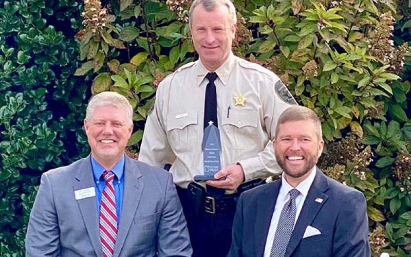 Fannin County Sheriff Dane Kirby, standing, was presented the Fannin County School System’s Pioneer in Education award by Pioneer RESA Executive Director Justin Old, seated left, and Fannin County School Superintendent Dr. Michael Gwatney.