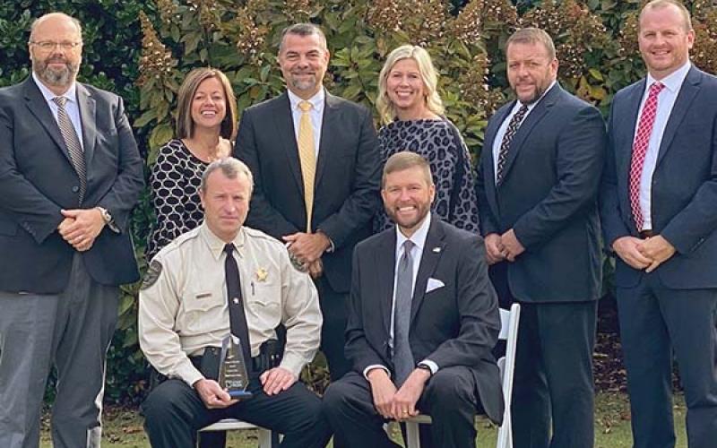 Fannin County Sheriff Dane Kirby, seated left, holds his Pioneer in Education award. Shown with the sheriff following the award ceremony are School Superintendent Dr. Michael Gwatney, seated, and standing from left, Fannin County Middle School Principal Mark Young, West Fannin Elementary Principal Allison Danner, Assistant Superintendent Darren Danner, Blue Ridge Elementary Principal Dr. April Hodges, Fannin County High School Principal Dr. Scott Ramsey and East Fannin Elementary Principal Mathew Price.