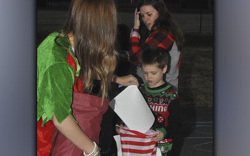 Santa’s helper Cassidy Payne give Koen Williams some gifts while he makes his way to meet Santa Claus during the Winter Wonderland event at the Fannin County Recreation Center Friday, December 3.