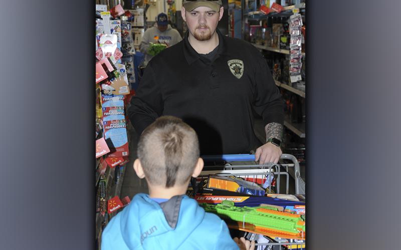 Sergeant Evan Asbury helps a child pick out Christmas toys during Shop With a Cop.