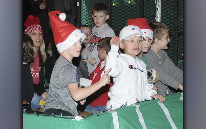 A young man throws candy to the crowd gathered for the Ducktown Christmas parade while  his friend  urges him to be careful.