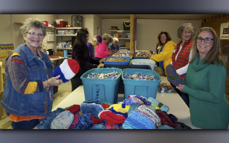 Kim King, left, and Jane Meyer worked together to knit hats to go in the Snack in a Backpack bags for children before Christmas.