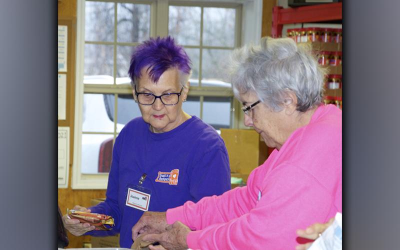 Snack in a Backpack volunteers Joanne Campbell and Anne Brayley help to pack bags of meals to be distributed to children in local schools.