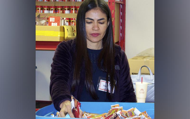 Snack in a Backpack volunteer Danis Place grabs some granola bars to be placed in meal bags to be distributed to local school children during a packing day Wednesday, December 8.