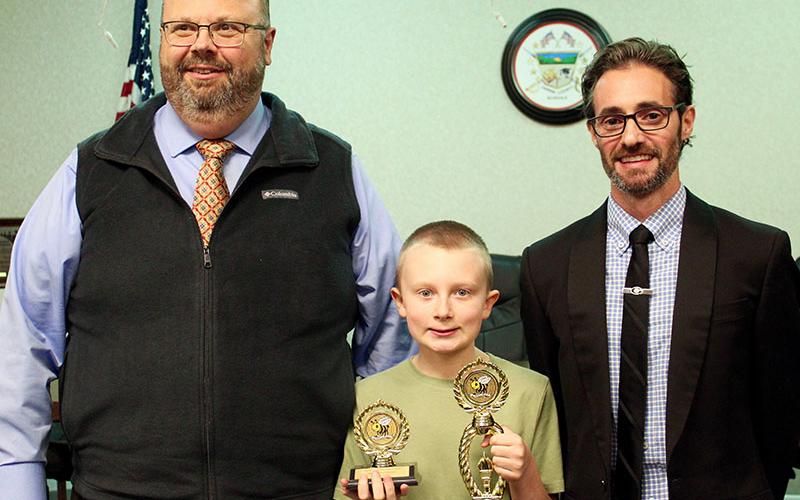 Fannin County Middle School (FCMS) sixth-grader Dylan Hart, middle, proudly holds his trophies after winning the Fannin County School System Spelling Bee, Tuesday, January 25. Shown with him are, FCMS Principal Mark Young, left, and Fannin County School System Director of CTAE/STEM and Spelling Bee caller Lucas Roof, right.