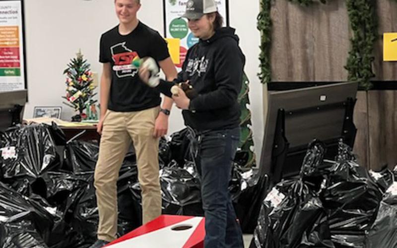 Toys for Tots volunteers Bryce Ware, left, and Dustin Long enjoy a game of cornhole while they wait for folks to come pick up their children’s toys.