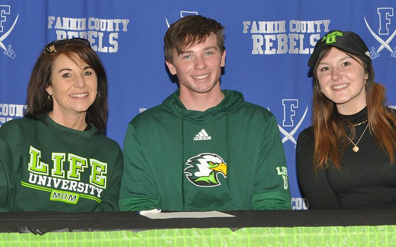 Rebels soccer player Payton Roath smiles after signing to play soccer for Life University. He is accompanied by his mother Tiffany Roath, left, and his sister Cassi Roath.