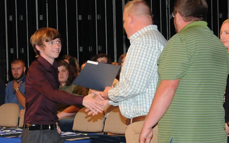 Dallas Trent Lowery is all smiles as he is presented a David Curtis Memorial Scholarship to fund his education as an emergency medical technician. Curtis’ sons, Josh, presenting the award, and Matt, attended Fannin County High School Awards Day to present the scholarship.