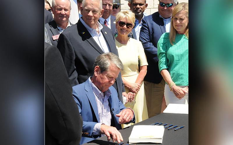 Georgia Governor Brian Kemp, seated, signed the state’s 2023 budget during a special ceremony Thursday, May 12, on the University of North Georgia Blue Ridge campus. Behind Kemp are District 7 Representative and Speaker of the House David Ralston and his wife, Sheree Ralston, Fannin County economic development director.