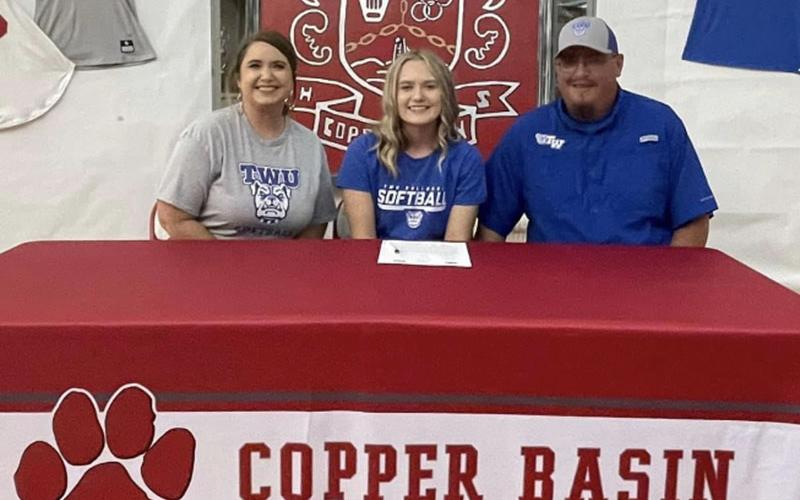 Copper Basin senior softball player Channing Beach smiles after signing her letter of intent to play softball at Tennessee Wesleyan University Thursday, May 5. She is accompanied by her parents Tina Hayes and BJ Howard.
