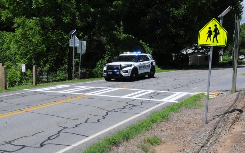 McCaysville police officers are promising strict enforcement of the 25 miles-per-hour speed limit in the area of the new crosswalk on Toccoa Avenue/Highway 60 in front of Rolling Thunder River Company. This is the site, shown above, where a ten-year-old boy was killed as he attempted to cross the highway in 2013. With the river tubing season in full swing, the area is congested with traffic and pedestrians.