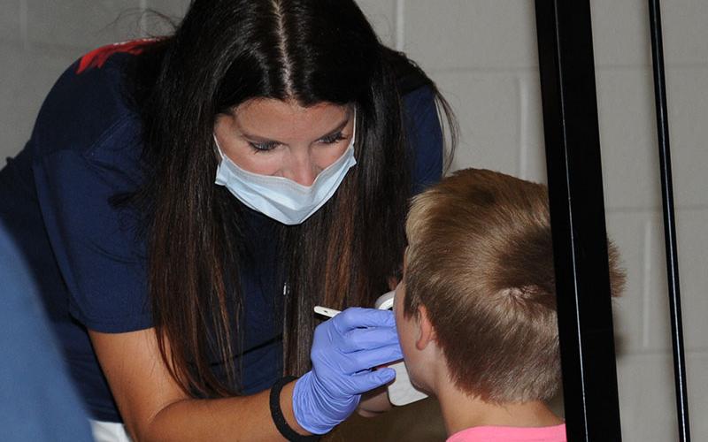 Heather Howard with Georgia Mountains Health does a dental check on one of the over 300 young people who took advantage of the Summer Bash Saturday.