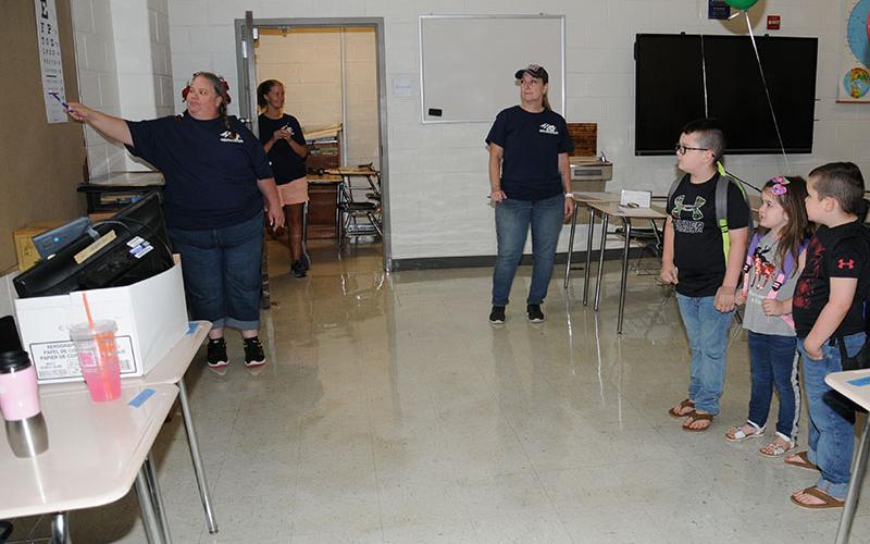 Derek, Caylee and Creed Davis, from left at right, were given vision screenings by Michelle Maldonado of Georgia Mountains Health. Helping, also from Georgia Mountain Health, were Katie Harrison and Joey Brown. A total of 225 children took advantage of the free scrennings.