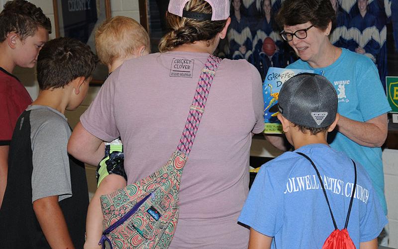 TC Dillard, right, kept busy handing out books to young people during the Summer Bash.