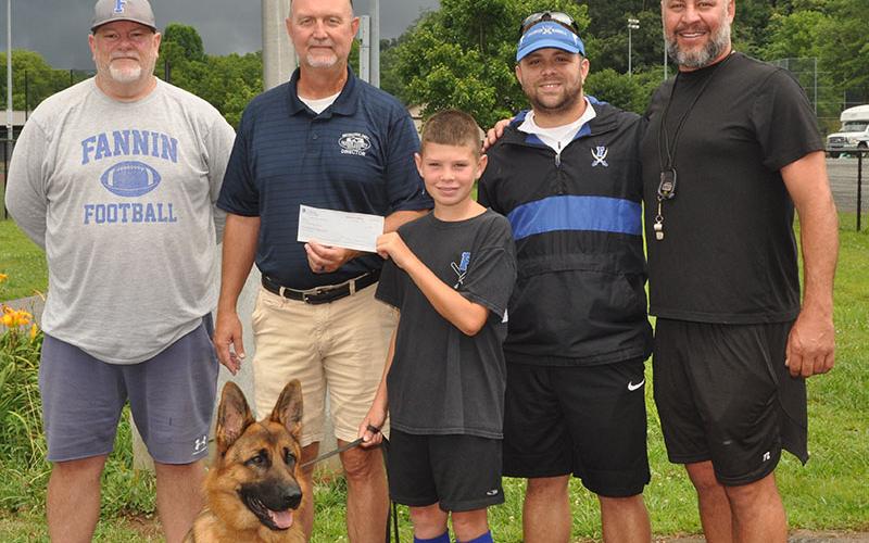 Ten-year-old Clay Maddox presents his $1,000 donation to Fannin County Recreation Department representatives to help pay fees for children who would like to play sports but cannot afford to register. Shown are, from left, John Spargo, Eddie O’Neal, Clay Maddox, Tim Towe, Earl Maddox and, in front, Clay’s dog Maverick.