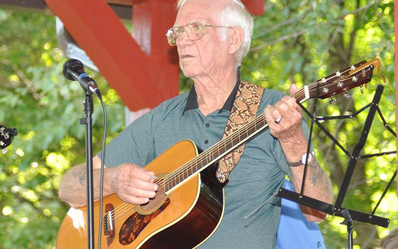 While looking over to a fellow picker, this gentleman strums his guitar at Pickin’ In The Park Thursday, July 14.