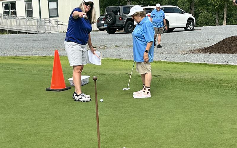 Carrie Minear, left, points athlete Kari Castlen to the hole at the Special Olympics golf event Tuesday, July 19 at Old Toccoa Farm.