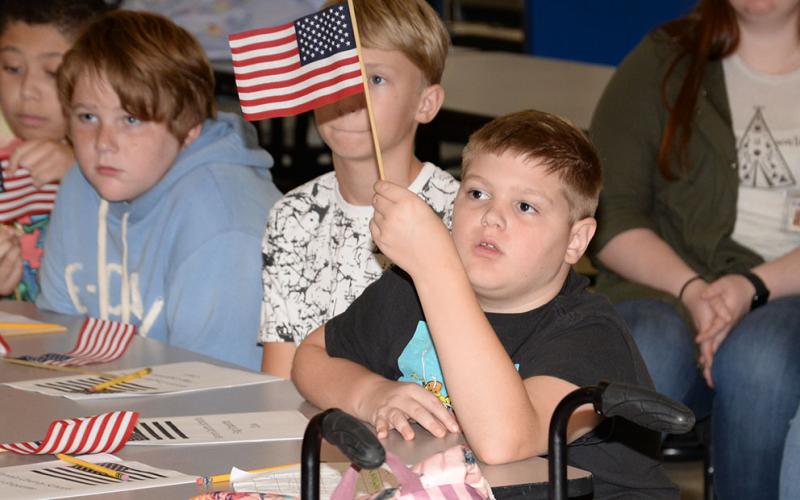 Caleb Gowin is pictured as he shows patriotism by waving the American flag during the flag etiquette class.