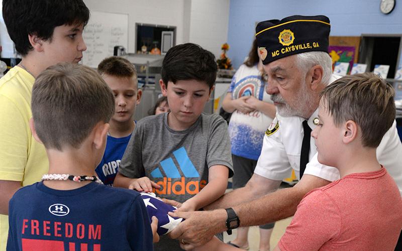 Veteran Steve Strickland helps a group of Blue Ridge Elementary students properly fold an American flag. From left, are Lee Stuart, Joseph Partin, Darran Bishop, Strickland and Mason Hampton.