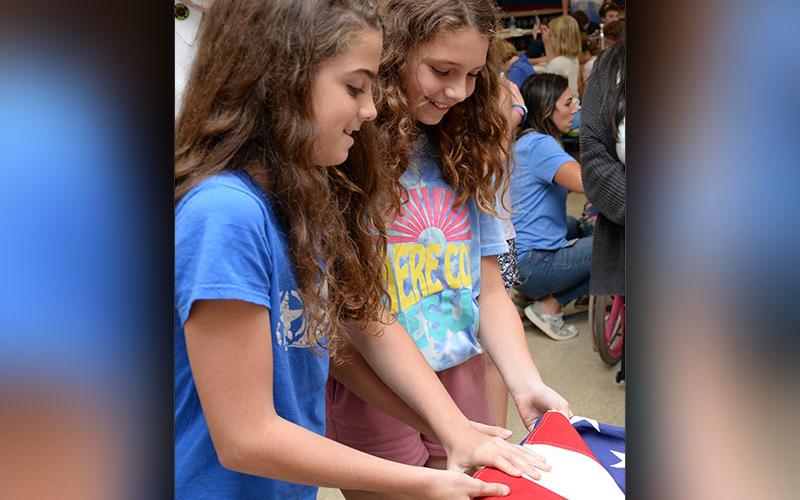 Jordan Hennessey and Kayley Martin carefully fold a United States flag during a Flag Etiquette class taught to Blue Ridge Elementary School students by local veterans.