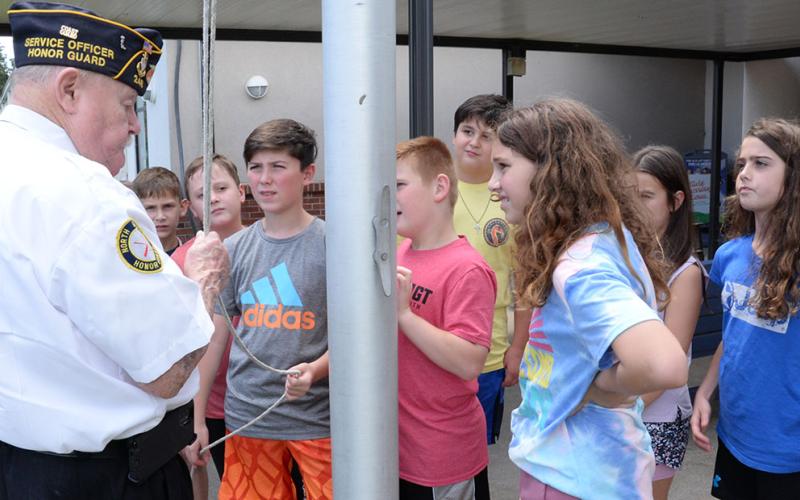 Gerald “Chief Mac” McMillan, left,  demonstrated the proper way to raise and lower the American flag for this group of students at Blue Ridge Elementary School.
