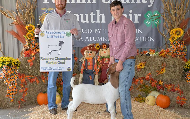 Jacob Williams, a Fannin County High School FFA member, holds onto his prize goat as liverstock judge Dylan Davis displays his award.