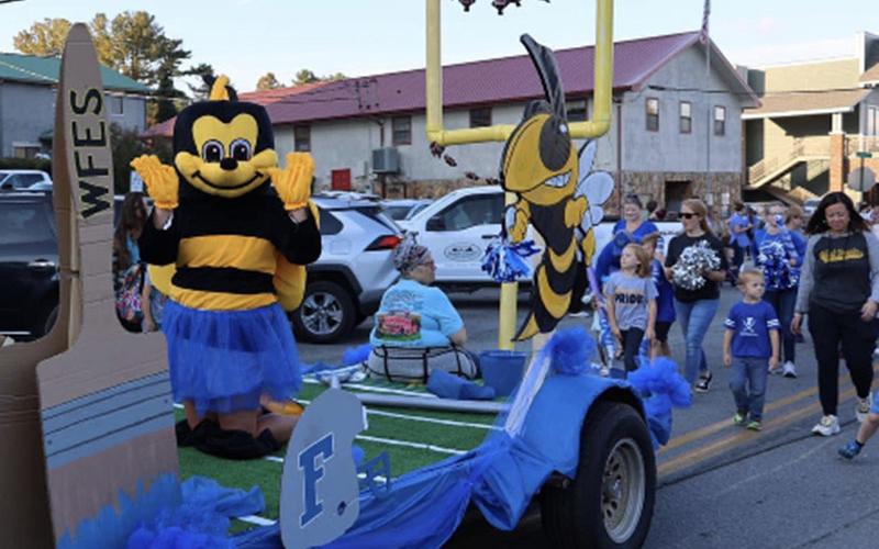West Fannin Elementary School’s Yellow Jacket waves from the float while Principal Alison Danner walks behind with a group of students in the Paint the Town Blue Homecoming Parade through downtown Blue Ridge Tuesday, October 11.