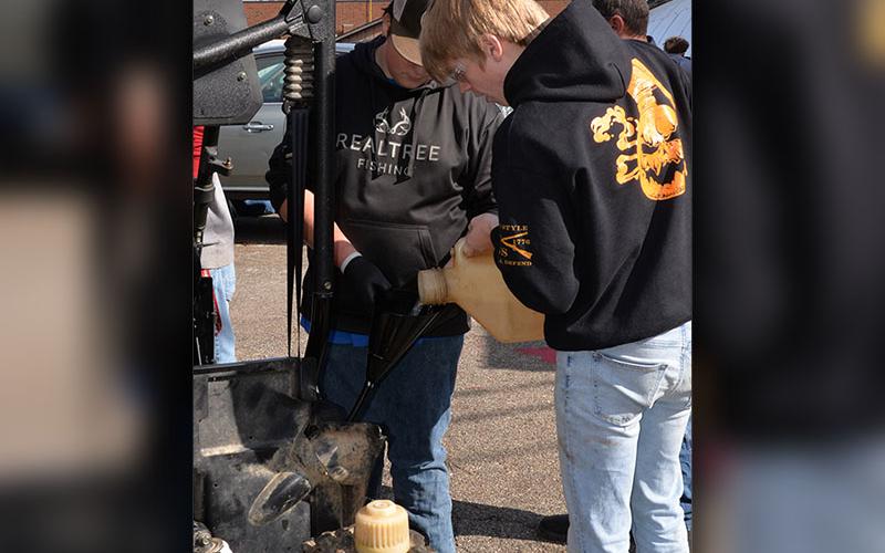 Joseph Farmer and Dakota Rutledge add gasoline as they work with a team to get a four-wheeler started in Automotive Technology at Fannin County High School.