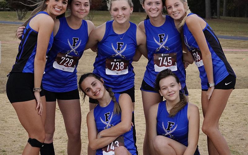 The Lady Rebels cross country team smiles together after earning first place in the Region 7AA Championship meet in Rome for the third year in a row Tuesday, October 25. Shown are, from left, standing, Monica Cosentino, Kristin Cipich, Shaylee Jones, Olivia Temples and Lindsey Holloway; and kneeling, Karli Sams and Jaclyn Cracknell.
