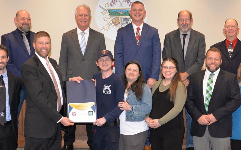 The Fannin County Board of Education honored Trent Lowery for his part in a Fannin County Emergency Medical Services call that resulted in the full recovery of an 88-year-old stroke victim. Shown during the presentation of a certificate at the board’s December meeting are, from left, front, Chief Academic Officer Lucas Roof, School Superintendent Dr. Michael Gwatney, Lowery, his mother and sister, Felicia Cowan and Alicia LeRoy, Fannin County High School Principal Dr. Scott Ramsey, Executive Director/Upcomi