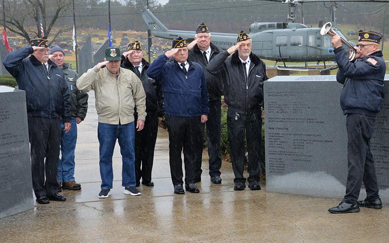 Rain fell as Richard Crosley, right, played taps at the conclusion of the Pearl Harbor Memorial Ceremony. Shown honoring those who gave their lives that day are, from left, Bill Stodghill, Kevin O’Quinn, Larry Dyer, Gerald “Chief Mac” McMillan, Ronnie Rabun, Ron Wallace and Steve Strickland.