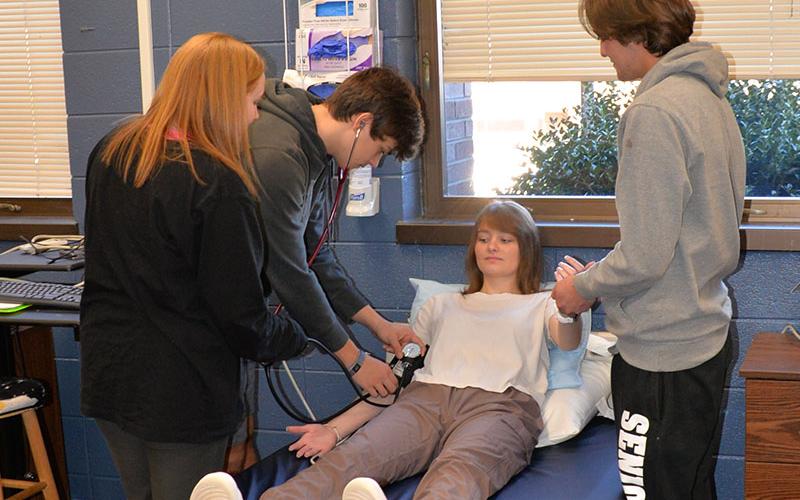 Taking a patient’s blood pressure and pulse are among the basic health care skills Certified Nursing Assistant (CNA) students learn at Fannin County High School. Here, using Clare Payne as the patient, Ivy Hyde, Hayden Danner and Micheal Treon practice the skills.