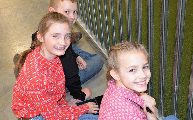 Owen Norton, Lola Temples and Ana Temples, back to front, are all smiles as they take a break between classes at the Pigs on the Ridge Invitational Market Hog Show last week at the Fannin County Agriculture Facility. All three of the youngsters came away from the show with honors.