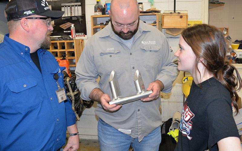 Fannin County High School welding instructor Terry Flowers, left, and advisory board member Devin Johnson, admire the work of student Emmaline Cochran, right.