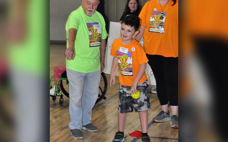 Camden Shook from Blue Ridge Elementary competes in the Special Olympics softball toss under the watchful eyes of Tom Newman and Samanthan Goswick.