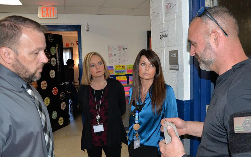 Corporal David Ridings, right, with the Gilmer County Sheriff’s Office, describes the bait used to train drug detecting dogs to, from left, Fannin County High School Principal Dr. Scott Ramsey and assistant principals Heather Collis and Mandy Housley. After a thorough search of FCHS last week, the five dogs used were put through a training exercise in one of the classrooms.
