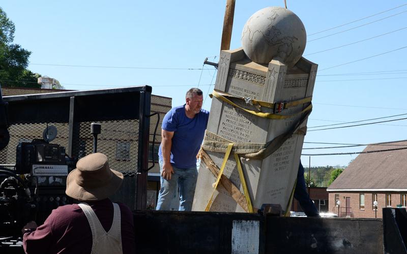 Lee Dillard operates the crane moving the Veterans Monument as Albert Queen helps guide it into position.