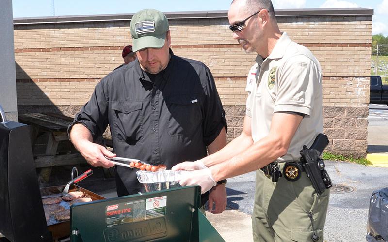 School Resource Officers and Fannin County deputy sheriffs Jim Burrell, left, and Lieutenant Darvin Couch were busy getting hamburgers and hotdogs ready for the participants in Saturday’s Riding the Ridge to benefit Shop With a Cop.
