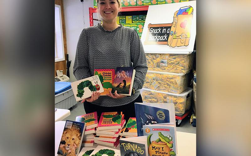 Cayley Hamilton  is shown, at the Book Dropoff 2023, unboxing the books for the Feed and Read Fannin event.