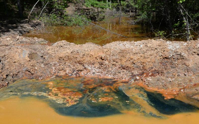 The orange water is the ground water/mine water at the head of the Copperhill Industries area. Buddy Haynes explains that is the color before the water is treated with biosolids through a series of ponds. At this stage it is about a pH2. Once treated, it turns green, as is seen above, and the pH level reaches 6 to 8, which is capable of sustaining aquatic life.