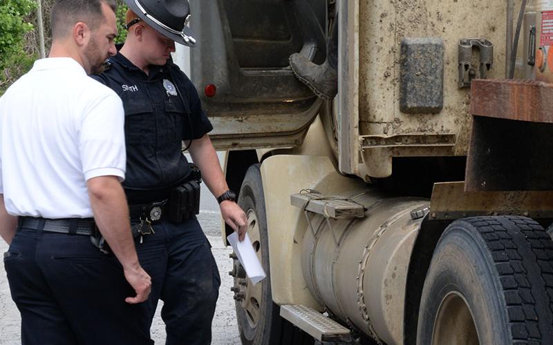 McCaysville Police Chief Michael Earley, lefrt, and Officer Hayden Smith of the Motor Carrier Compliance Division inspect an Atomic Transport 18-wheeler after it was stopped last week.