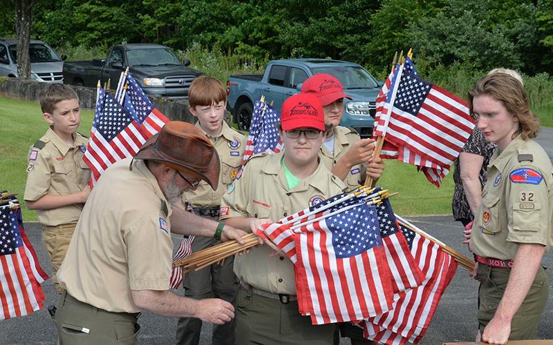 Scoutmaster David Lewis passes out United States flags to be placed on the graves of veterans at Crestlawn Cemetery to, from left, Troop 32 boy Scouts Stephen Young, Dakota Davis, Clay Dillard, Roy Green, Maddix Trantham, and Matthew Monroe. Placing the flags at the cemetery has long been an annual project of Troop 32.