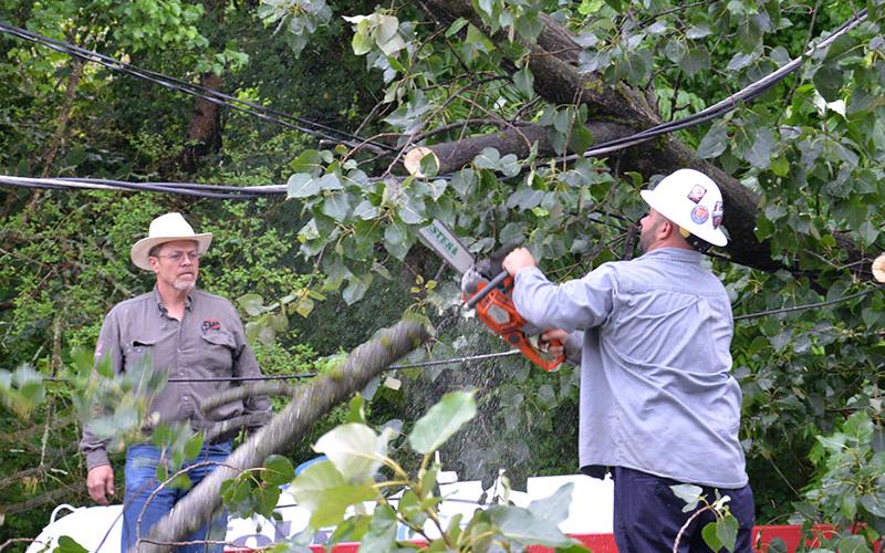 Travis Sisson cuts part of a tree away from the Pick Quick market in McCaysville so power can be restored to the business.