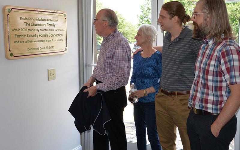 Glenn Chambers reads the plaque on the wall at the entrance to Fannin County Family Connection recognizing his family for their donation of the building. He is joined by his wife, Lynda, and their sons, Chris and Patrick.