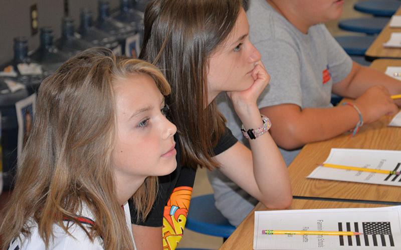 Ana Temples and Alex Kennan listen as Bill Stodghill explains proper respect for the United States flag during a presentation at Blue Ridge Elementary.