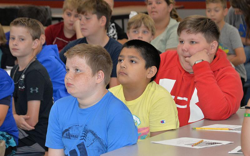 Bresnen Campbell, Aidan Vega, and Brantlee Norton, front, watch and learn respect for the United States flag.