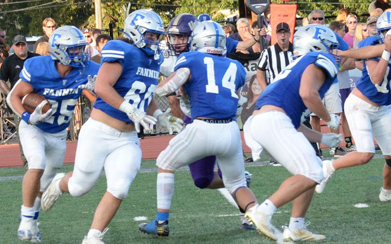The Fannin County High School Rebels work together to defeat the Gilmer County Bobcats Friday, August 25, 38 to 14. Rebel Carson Callihan (#25) runs the ball while his teammates Jacob Dye (#60), Cooper Born (#14), Case Holloway (#62), and Noah Burnett (#72) work hard to create a hole for him to run through.  (Photo by Glenn Harbison)